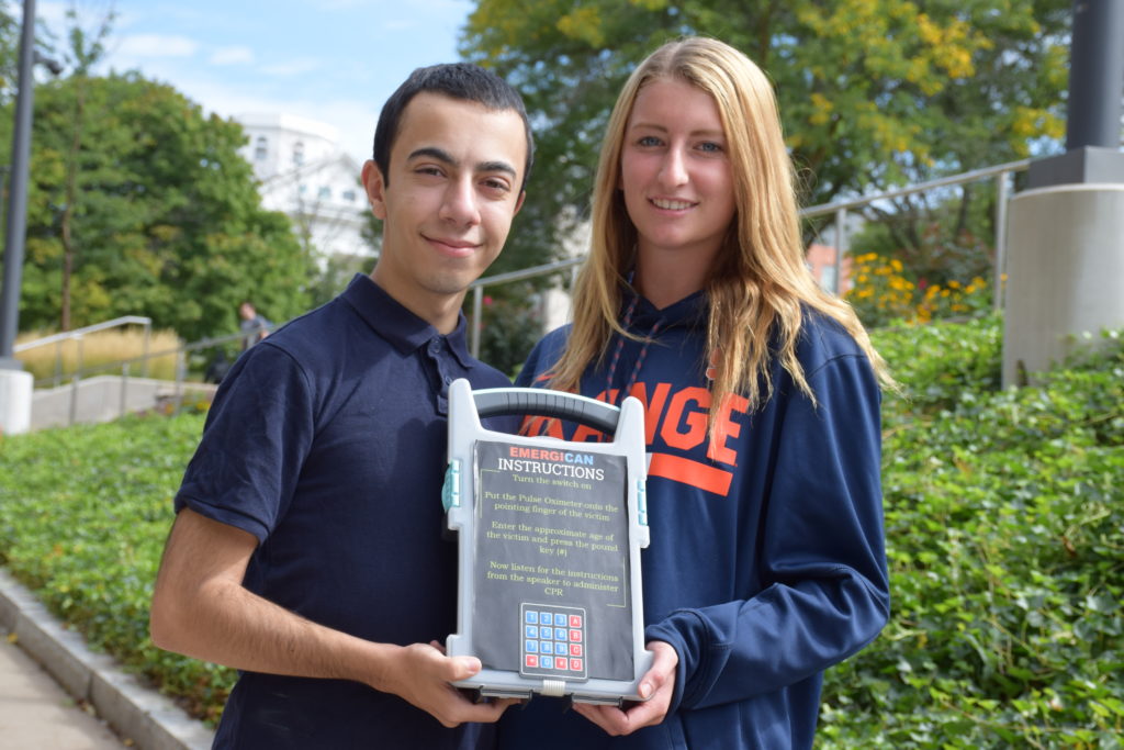 Two students stand together and hold up medical invention